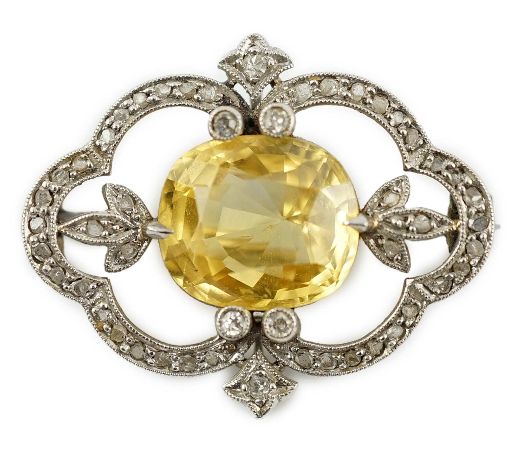 A Belle Epoque white gold, single stone yellow sapphire and diamond chip cluster set open work brooch